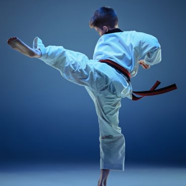 young-boy-training-karate-on-blue-background-PRBVLPM.jpg